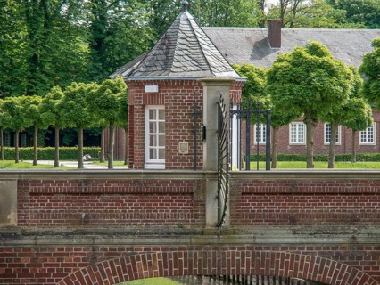A small brick building with a Tor tor, surrounded by trees and a well-kept courtyard on a summer's