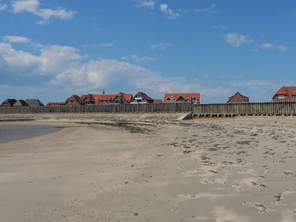 Empty beach with traces in the sand and traditional buildings in the background, Baltrum Germany