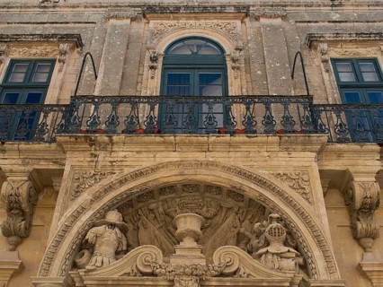 Close-up of a historic building with richly decorated balcony and stucco ornaments, the town of