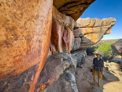 Young man looking at prehistoric depiction of woman on a rock, San rock paintings, Sevilla Art Rock