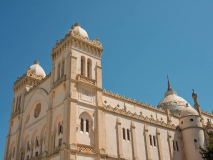 Large historic building with domes and decorations under a clear blue sky, Tunis in Africa with