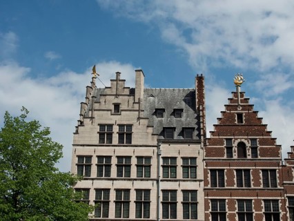 Two buildings with striking Renaissance and Gothic architectural elements under a blue sky,