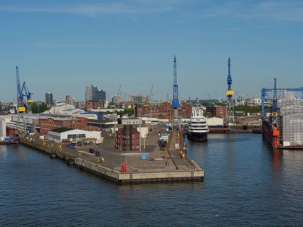 Industrial harbour area with cranes and ships in the water under a clear sky, Gorse city on the