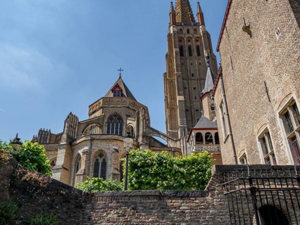 Gothic cathedral with high towers and brick walls on a summer day, historic houses and churches