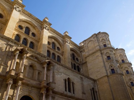 Historic gothic cathedral with stone walls and window arches under a clear blue sky, spring with