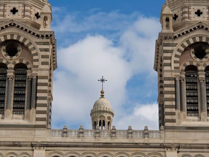 Detailed close-up of the spires and a cross of a historic cathedral, blue sky in the background,