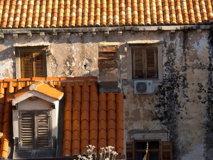Old buildings with red tiled roofs and closed shutters, partially dilapidated facades, the old town
