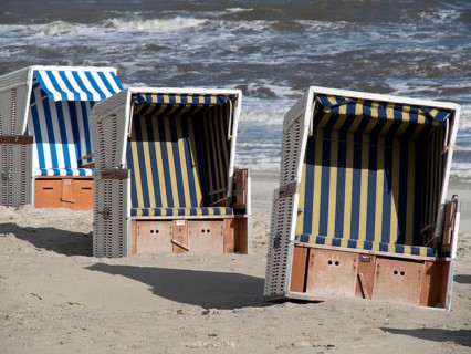 Three beach chairs in blue and white design on the beach in front of the sea, beach chairs on the