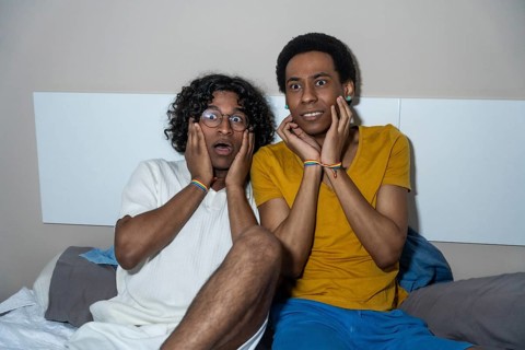 Gay latin male couple watching a horror movie at night at home