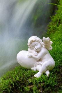 Porcelain angel figurine on moss by a waterfall