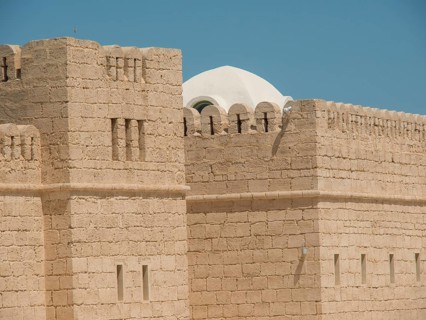 Stone walls of a historic fortress or castle with dome and clear sky, Tunis in Africa with ruins