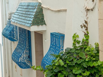 White building wall with decorative blue balconies and green roof tiles, Tunis in Africa with ruins