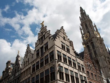 Historic buildings with ornate gables and a bell tower in the background under a blue sky with