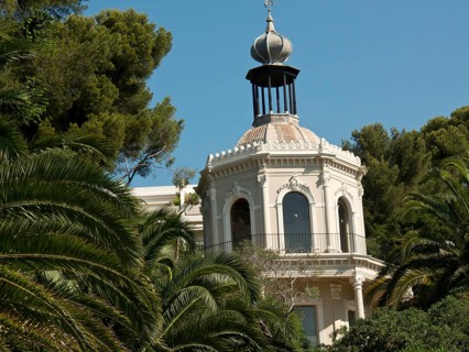 An elegant villa tower rises into the sky between the densely overgrown palm trees, la seyne sur