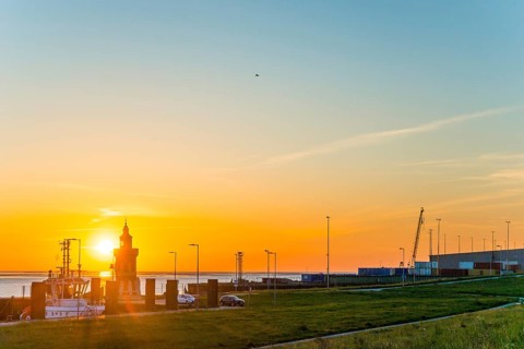 Pingelturm, historic lighthouse at the harbour at sunset, with calm sea, boats and green meadow in