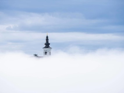 Church tower rises out of the morning mist, Frauenberg pilgrimage church, near Leibnitz, Styria,