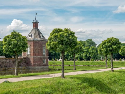 A small brick tower with manicured trees along a path on a sunny summer day, historic castle with a