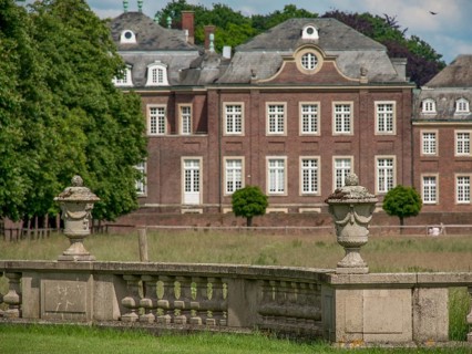 Stone vases in a green park, with a historic castle in the background, historic castle with a green