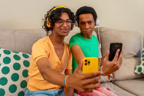 Gay couple listening to music and taking a selfie together at home