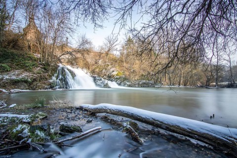 Beautiful landscape in winter with ice and snow. Waterfall of the river Elz near the castle