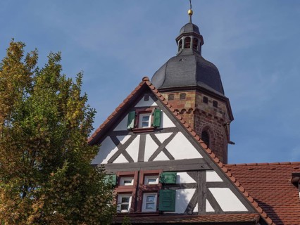 Church and half-timbered house with bell tower under a clear autumn sky, historic half-timbered