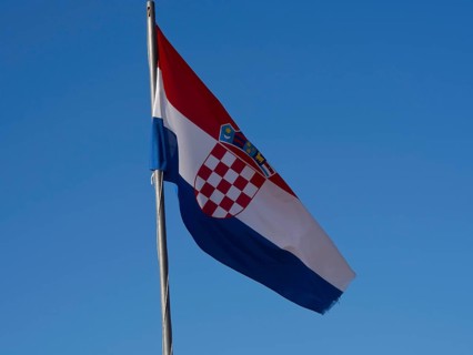 The Croatian flag fluttering in the wind against a clear blue sky, with its characteristic red and
