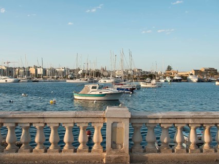 Harbour view with numerous boats on the calm sea and a stone balustrade in the foreground, Valetta,