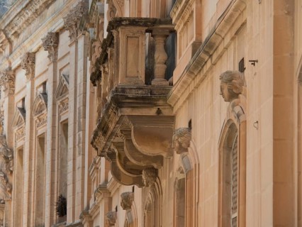 Side view of a historic building with decorative sculptures and balconies, the town of mdina on the