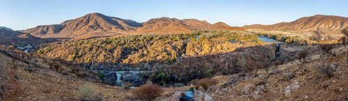 Panorama, Kunene River with green vegetation in dry red mountain landscape, waterfall and African