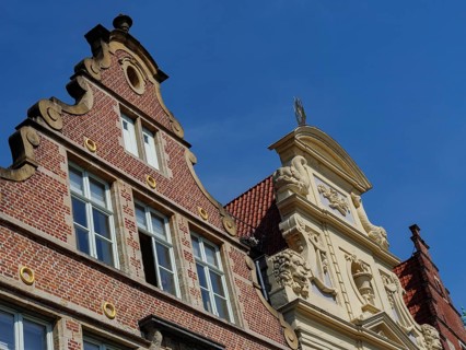 Historic brick building with decorative ornaments under a clear blue sky, medieval facades with