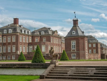 Imposing castle building in a park-like setting with clouds in the sky, historic castle with a