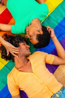 Vertical top view photo of a male latin gay couple caressing over a LGBT rainbow flag