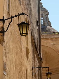 Historic lantern along an old wall with arch structure and blue sky in the background, Historic