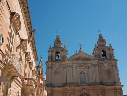 Baroque church with two bell towers in the bright blue sky, the town of mdina on the island of