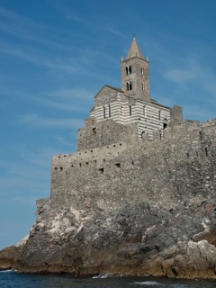 A historic stone church perched on rocky cliffs on the coast against a clear sky, Bari, Italy,