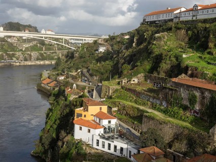 Buildings and green landscapes in a valley next to a river, under a cloudy sky, spring in the old