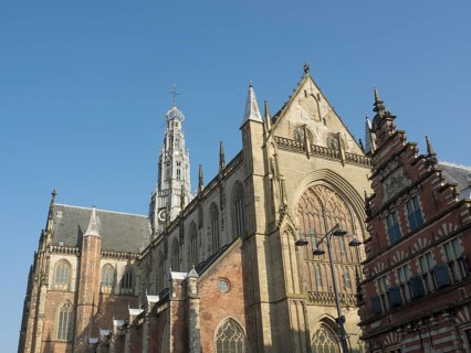 View of a Gothic church and neighbouring historic buildings under a clear sky, Haarlem, Netherlands