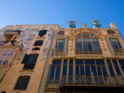Decorative building with artistic mosaic work on the facade and several balconies under a clear