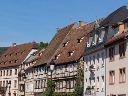 Historic half-timbered houses with red roof tiles and shutters under a blue sky, historic house
