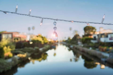 A string of lights and a quartz crystal are hanging on a string above a canal at Venice Beach,