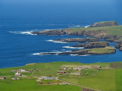 Coastal landscape with green fields, scattered houses and rocky cliffs by the deep blue sea, Green