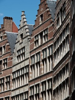 Row of historic brick buildings with stepped gables under a cloudless sky, Historic buildings on