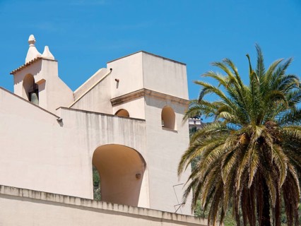 Mediterranean church with white walls and a palm tree under a clear blue sky in summer, palermo in