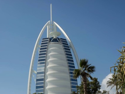 Close-up of the Burj Al Arab, a modern architectural icon, with some palm trees in the foreground