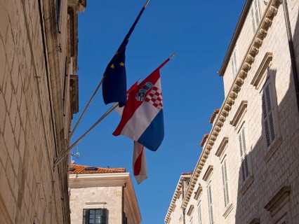 Flags of the European Union and Croatia fly in a narrow alley between historic buildings, the old