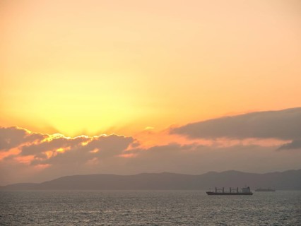 A large ship sails under an orange sunset on the calm sea, Tunis in Africa with ruins from Roman