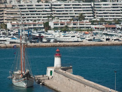 Harbour with a large sailing ship and a lighthouse, surrounded by blue buildings and yachts, ibiza,