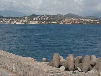 View of a coastal town across the sea, concrete breakwater in the foreground, Corsica, ajaccio,