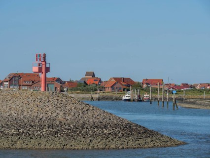 A harbour with red houses and boats moored on the shore, with a clear blue sky, Baltrum Germany