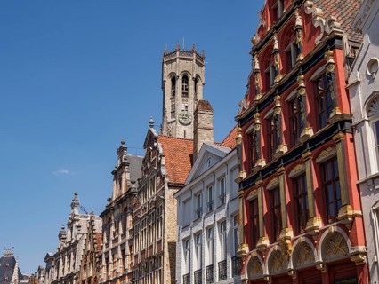 City scene with historic buildings with red facades and a bell tower under a clear blue sky,